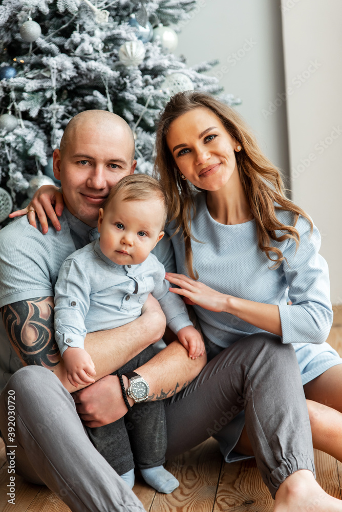 Happy young family of three near Christmas tree