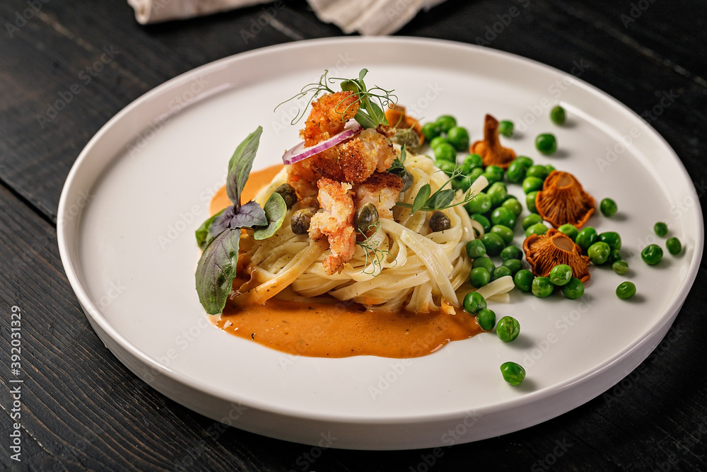 Pasta and fried shrimps with green peas and original chanterelle sauce. Healthy and tasty seafood. Signature dish.