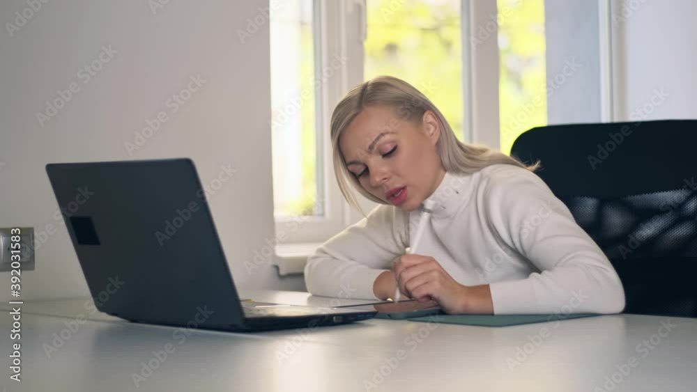 Young caucasian girl using laptop and tablet online learning in web. Woman sitting at table on home office. Working from home, working remotely and self isolation at home Young caucasian girl using laptop and tablet online learning in web. Woman sitting at table on home office. Working from home, working remotely and self isolation at home