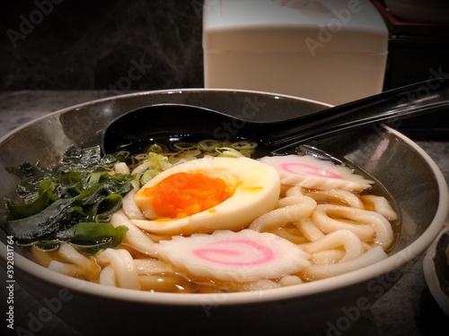 Close up view of Japanese Ramen with chicken tofu, nori, vegetables and yolk boiled egg in black bowl. Slate background. Selective focus background.

