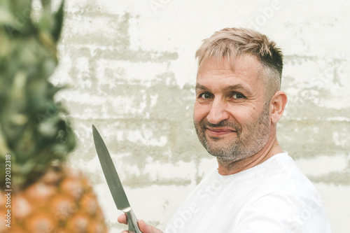 Stylish caucasian attractive chef with pineapple on a brick wall background. photo