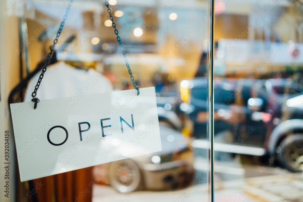 Φωτογραφία open sign welcoming customers hanging on glass door , in front of fashion clothi