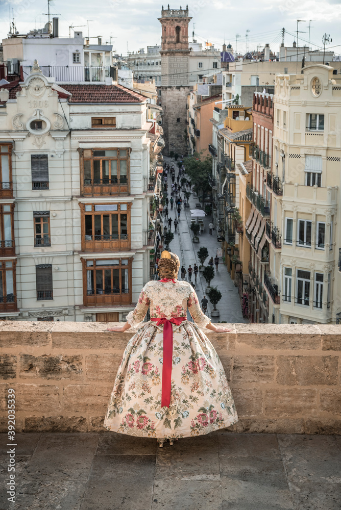 Woman with the traditional costume of the Fallas of Valencia. Woman leaning on a Moor enjoying the sunset in the old city of Valencia 2