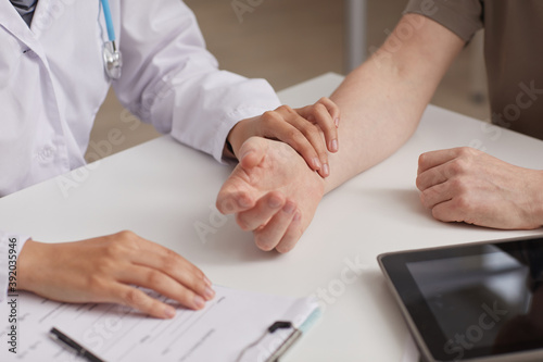 Close-up of nurse in white coat examining the patient during his visit she measuring his pulse