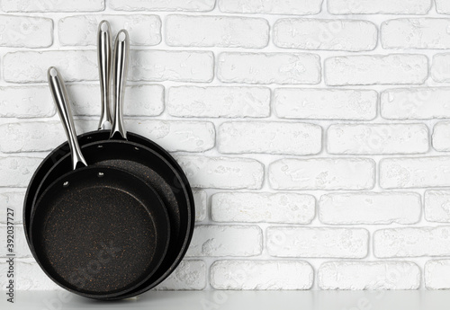 Fotótapéta Set of cooking pans against white brick wall