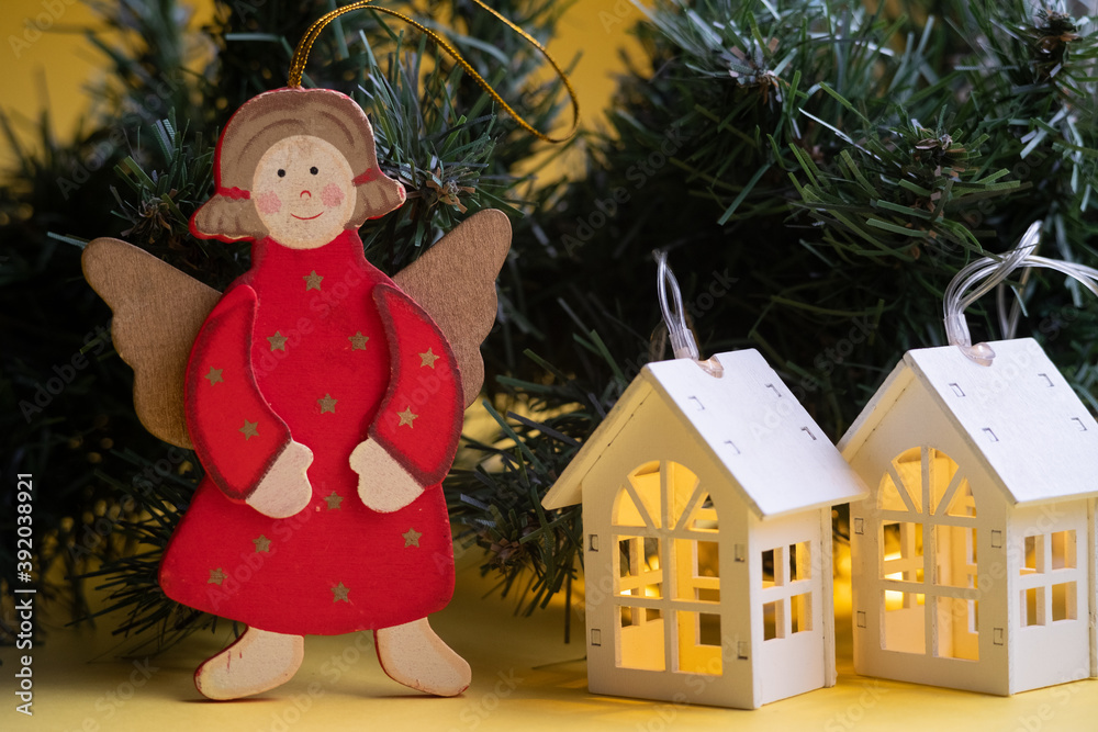 Christmas decorations on the tree, an angel and luminous houses garlands