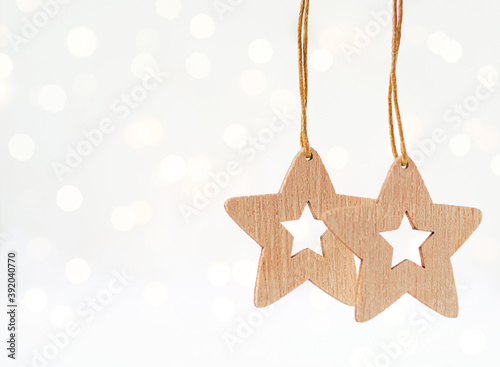 Wooden Christmas toy stars hang on a light background with bokeh