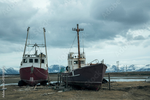 Ships moored at beach against cloudy sky