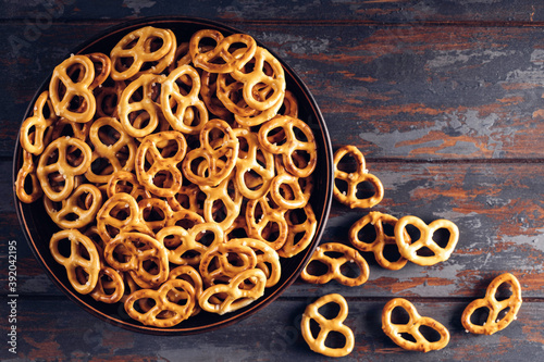 Hard pretzels or salted pretzels snack for party in bowl on wooden background. Top view.