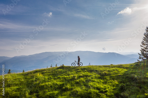 Mountain biker on his bike on a green hill on a sunny day photo