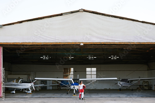 Young female skydiver in a plane hangar surrounded by planes photo