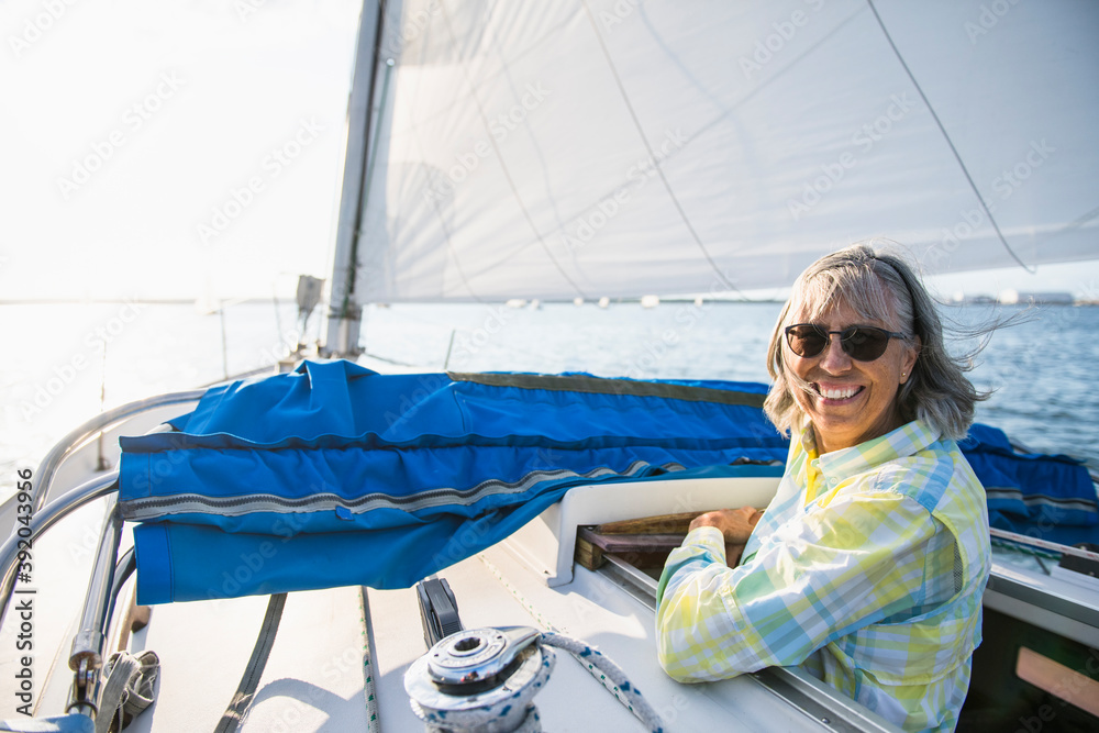 Middle age woman enjoying summer sail during golden hour Middle age woman enjoying summer sail during golden hour