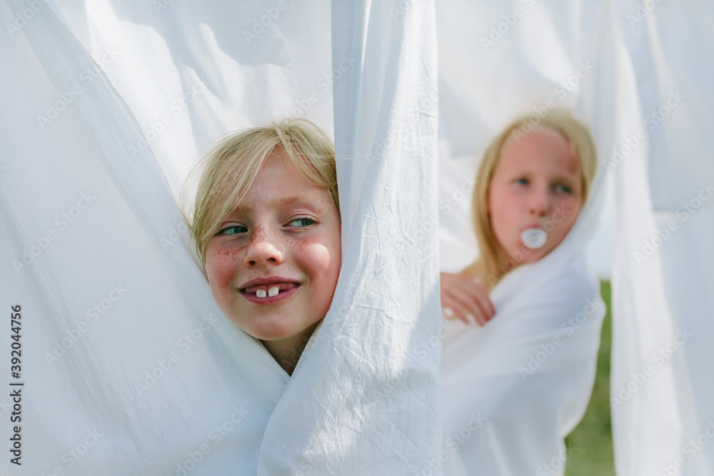 Children play hide and seek among the washed bed linen