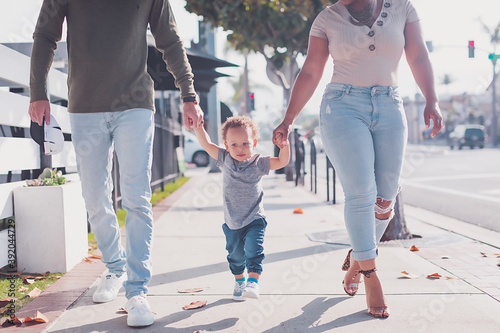 Family of three walking in Downtown, baby boy walking with parents photo