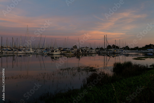 Boats in harbor during sunset with colorful sky reflecting in water photo