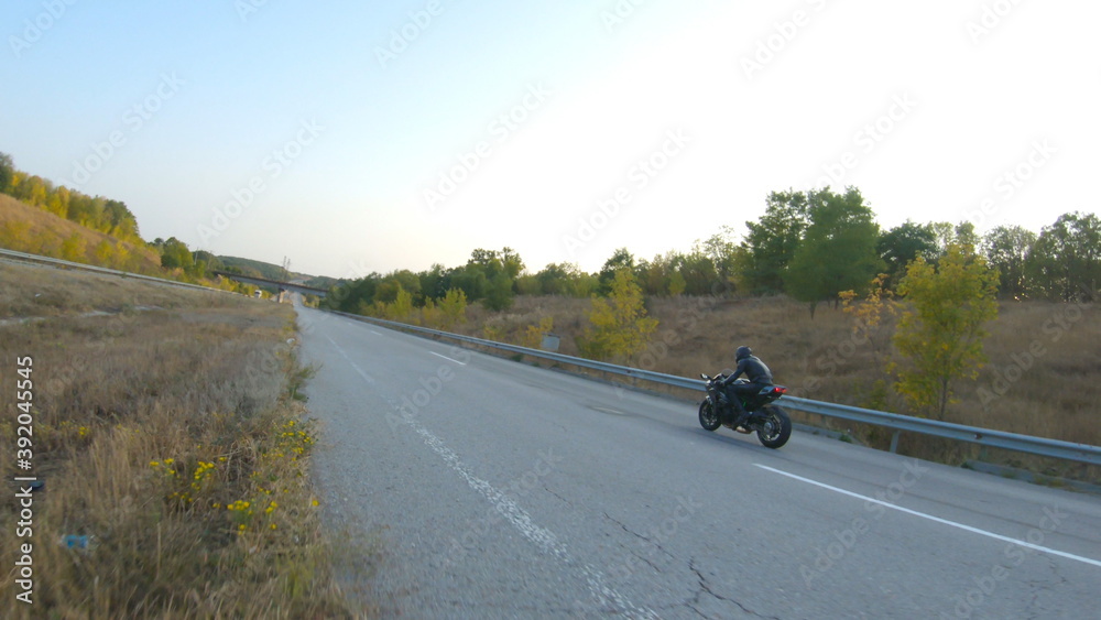 Follow to motorcyclist riding on modern sport motorbike at highway. Biker racing his motorcycle on country road. Guy driving bike during trip. Concept of freedom and adventure at journey. Aerial shot Follow to motorcyclist riding on modern sport motorbike at highway. Biker racing his motorcycle on country road. Guy driving bike during trip. Concept of freedom and adventure at journey. Aerial shot