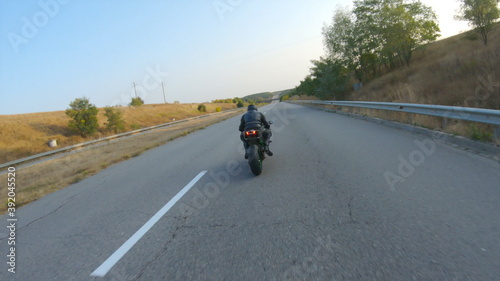 Aerial shot of man riding on modern sport motorbike at autumn highway. Motorcyclist racing his motorcycle on country road. Guy driving bike during trip. Concept of freedom and adventure. Above view © olehslepchenko