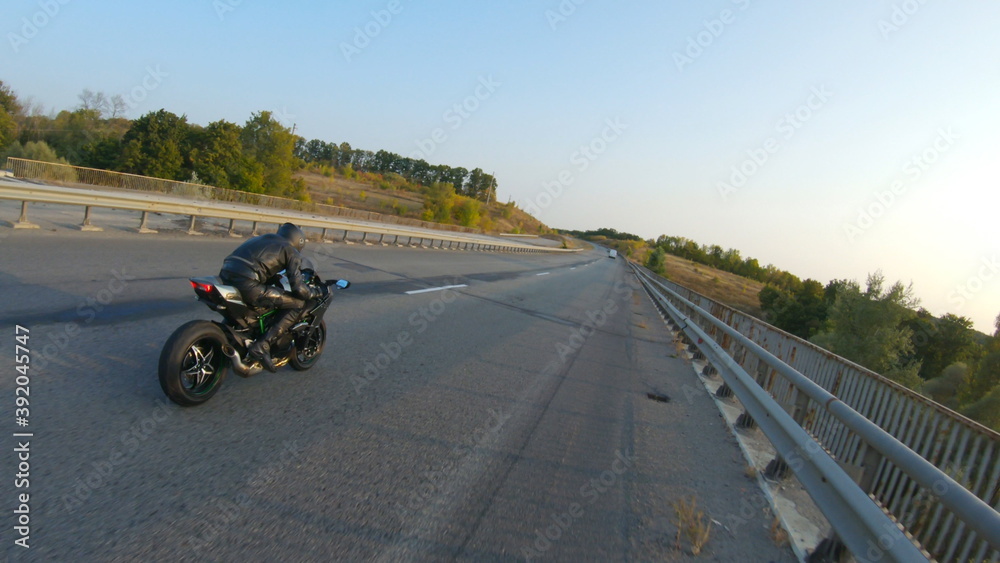 Follow to biker riding on modern sport motorbike at highway during sunny autumn day. Motorcyclist racing his motorcycle on country road. Guy drive bike during trip. Concept of journey. Aerial shot Follow to biker riding on modern sport motorbike at highway during sunny autumn day. Motorcyclist racing his motorcycle on country road. Guy drive bike during trip. Concept of journey. Aerial shot