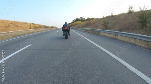 Follow to biker riding on modern sport motorbike at autumn highway. Motorcyclist racing his motorcycle on country road. Man driving bike during trip. Concept of freedom and adventure. Aerial shot