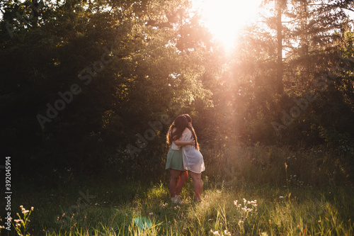 Lesbian couple embracing in forest during summer