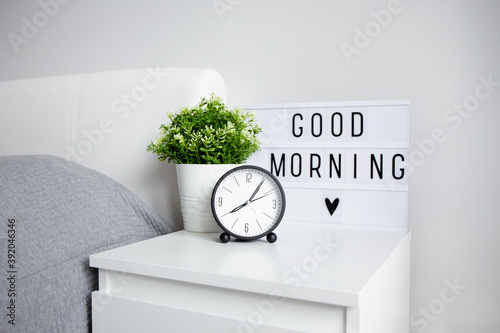 good morning concept - close up of alarm clock, houseplant and lightbox with 