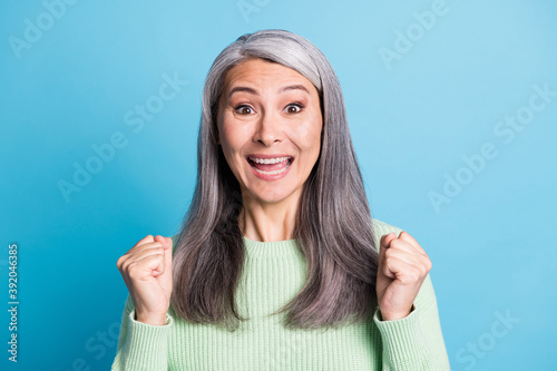 Portrait ofi amazed beautiful celebrating woman raise fists wear casual isolated on blue color background photo