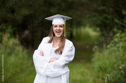 Laughing Female Graduate Wearing White Cap With Tassel and Gown photo