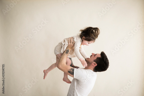 Happy Millennial Hipster Father Holds Toddler Girl Above His Head photo