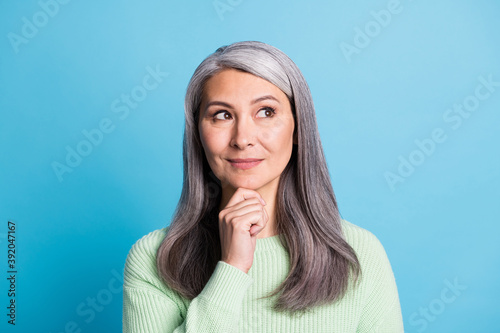 Photo of smiling curious aged woman dressed green sweater look empty space isolated on blue color background