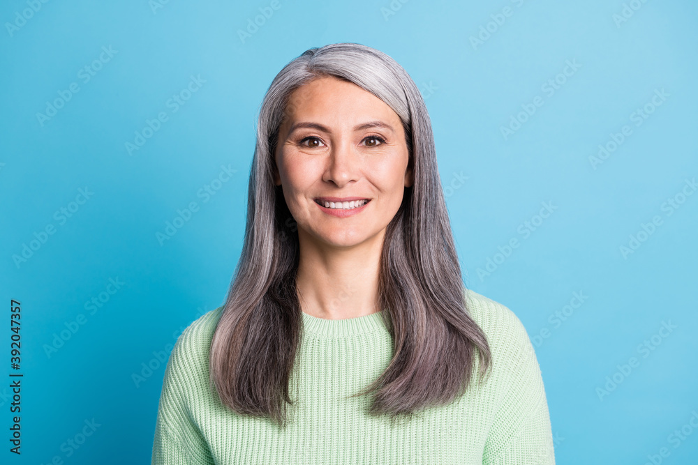Photo of smiling happy aged nice lady dressed green pullover isolated on blue color background Photo of smiling happy aged nice lady dressed green pullover isolated on blue color background