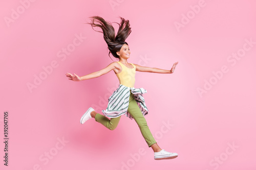 Full length photo of cute adorable school girl wear casual outfit jumping hands arms sides isolated pastel pink color background
