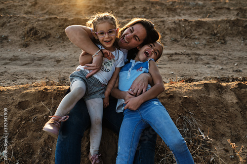 a mother sitting on the field plays with her daughters