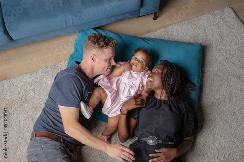 A biracial family laying on the floor with their daighter