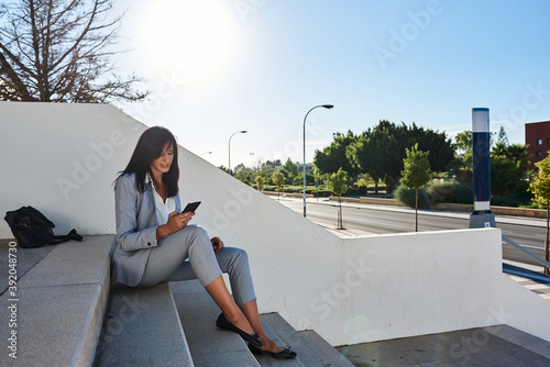 Businesswoman sitting on some stairs with smart-phone in hand. photo