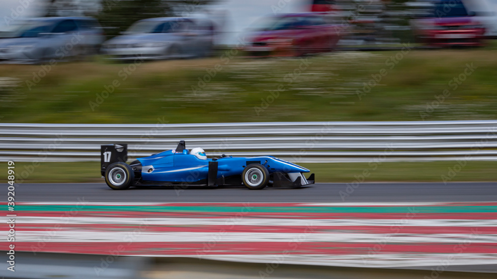 A panning shot of a racing car as it circuits a track.