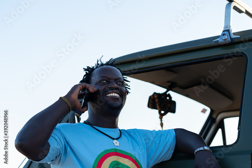 Middle aged black man smiling talking on the phone in his green campin photo