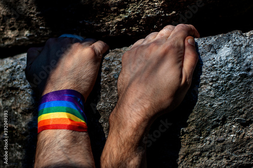 Two climber's hands with a gay bracelet hugging in the middle of a climb. photo