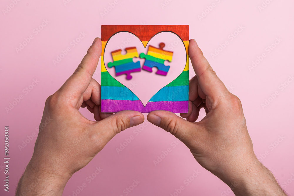 custom made wallpaper toronto digitalLGBT symbol frame heart in male hands inside puzzles painted by a rainbow on a medical mask. Coronavirus quarantine, online festival and International Day Against Homophobia.