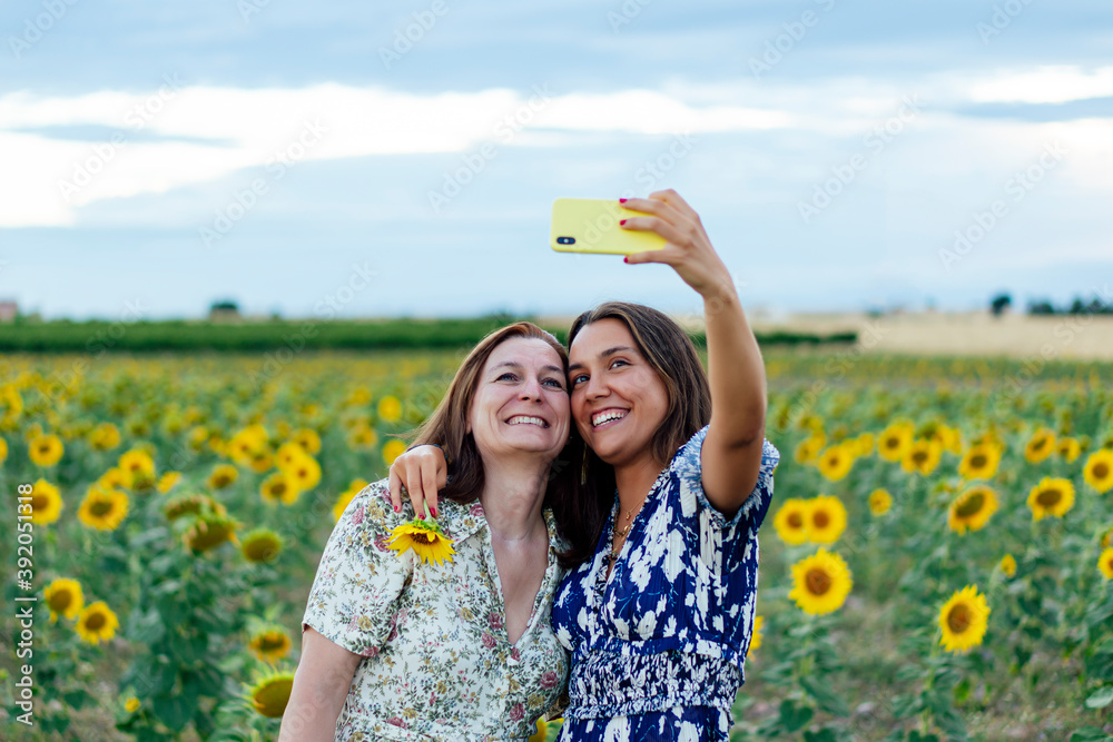 © Cavan Images - mother and daughter hugging taking a picture with the smartphone