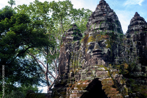 Angkor Archaeological Park, Siem Reap, Cambodia. Close up of Buddha's face on north gate of Angkor Thom surrounded by trees. photo