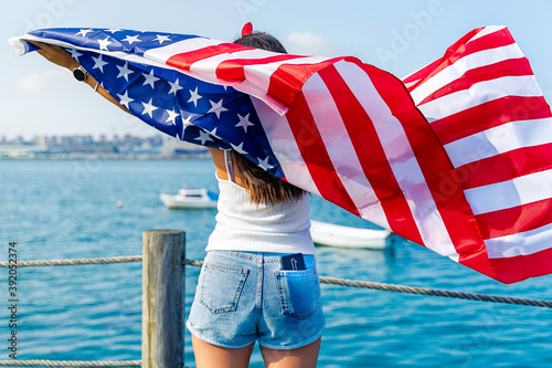 Young woman holding American flag with mobile phone photo