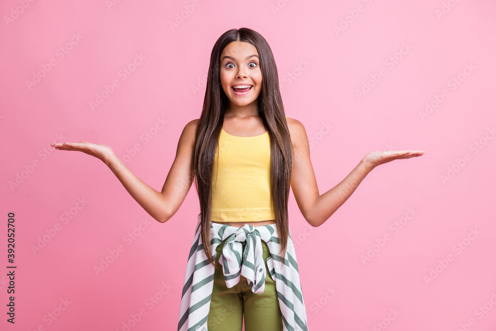 Photo of brown long haired trendy stylish shcoolgirl show hands empty space wear yellow singlet isolated on pink color background Photo of brown long haired trendy stylish shcoolgirl show hands empty space wear yellow singlet isolated on pink color background