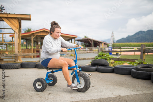 Fun expectant mother riding oversized tricycle on race track. photo