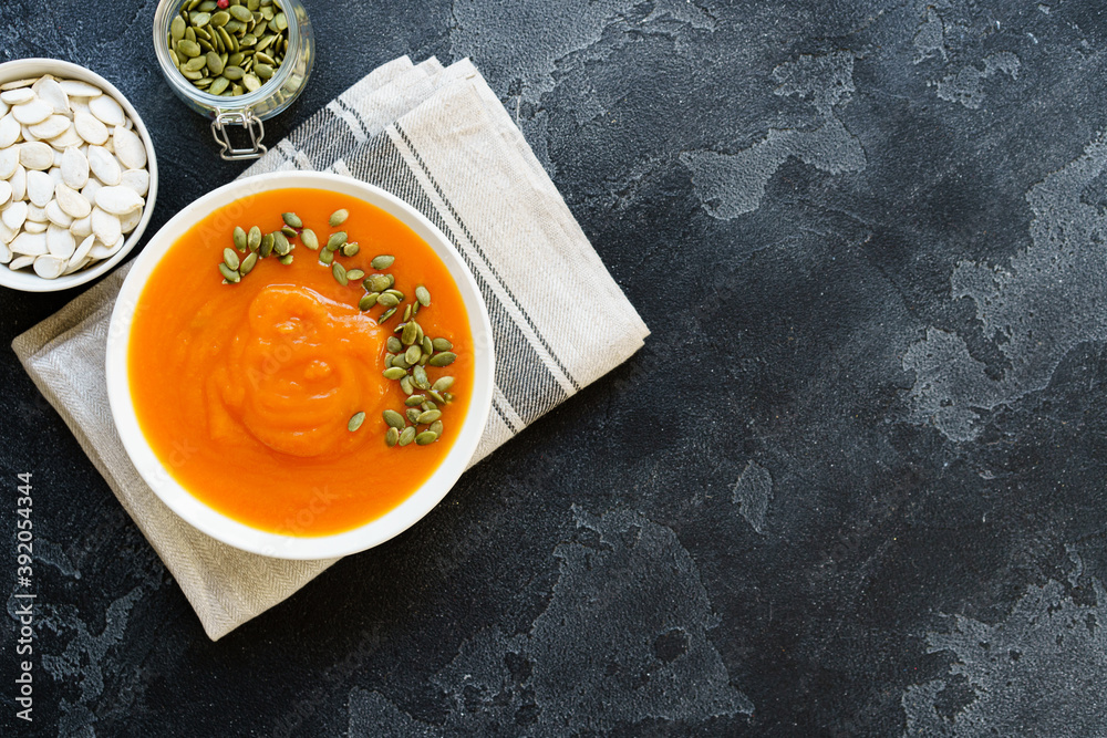 Top view of pureed pumpkin soup in a white bowl on dark table Top view of pureed pumpkin soup in a white bowl on dark table