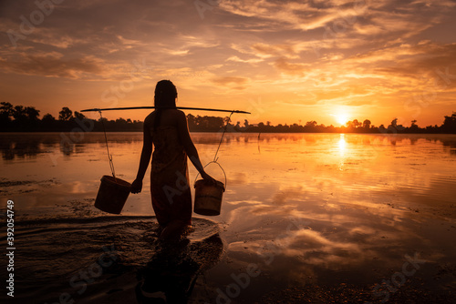 SRA SRANG,ANGKOR PARK, SIEM REAP, CAMBODIA - 17 August 2014: Local lady collects water in buckets over the shoulder for her garden from angkorian bathing pool. photo