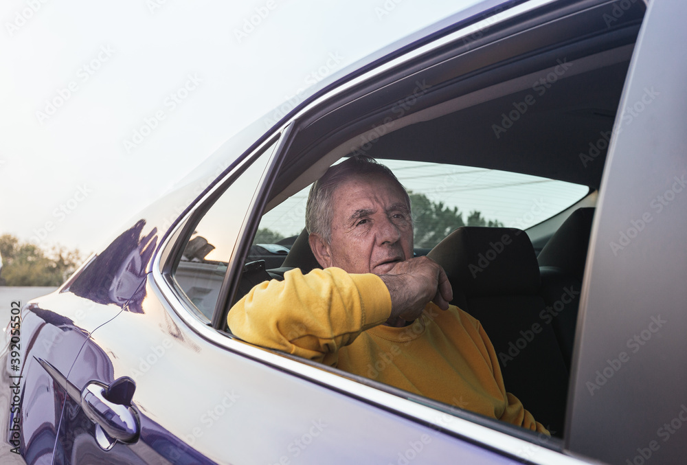 An old man sitting in the back seat of an electric car An old man sitting in the back seat of an electric car