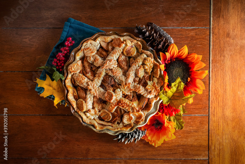 apple pie decorated with fall seasonal props on a kitchen table