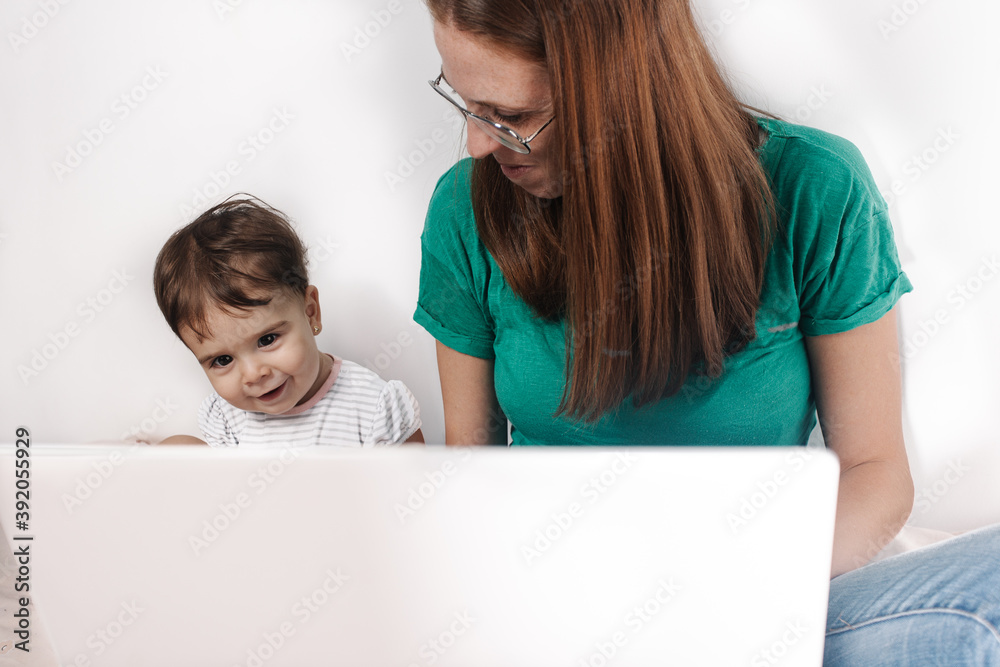 Mother looking a little kid using laptop at home Mother looking a little kid using laptop at home