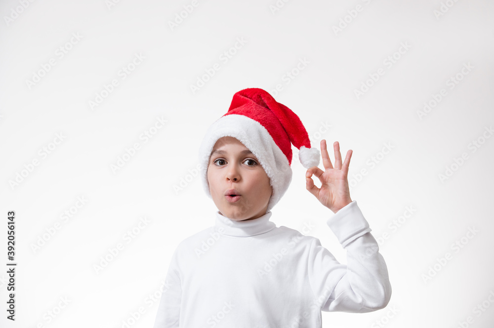 A boy in a red Santa hat shows a gesture of A boy in a red Santa hat shows a gesture of