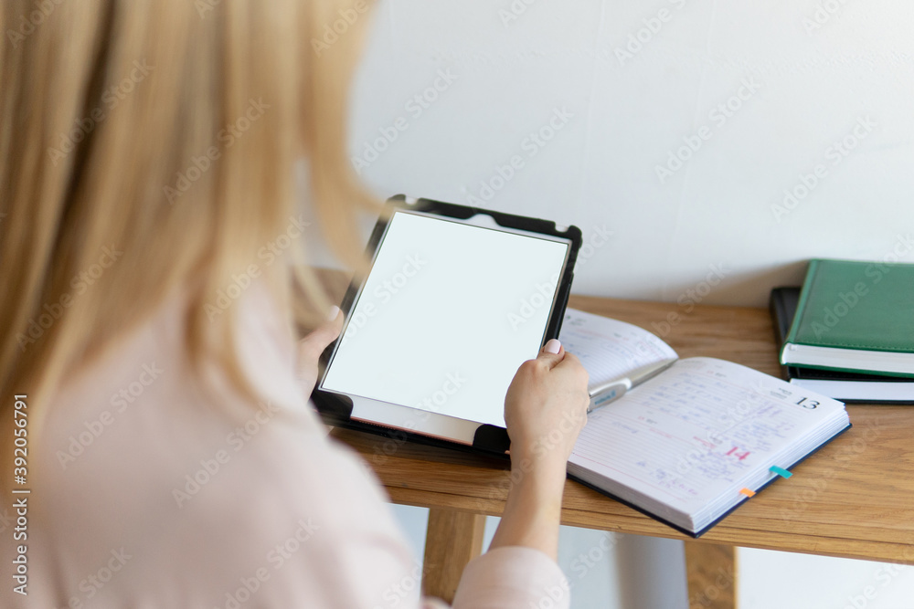 Online digital technology service concept. A girl with blond hair holds a tablet for business in her hands. blank screen mockup Online digital technology service concept. A girl with blond hair holds a tablet for business in her hands. blank screen mockup
